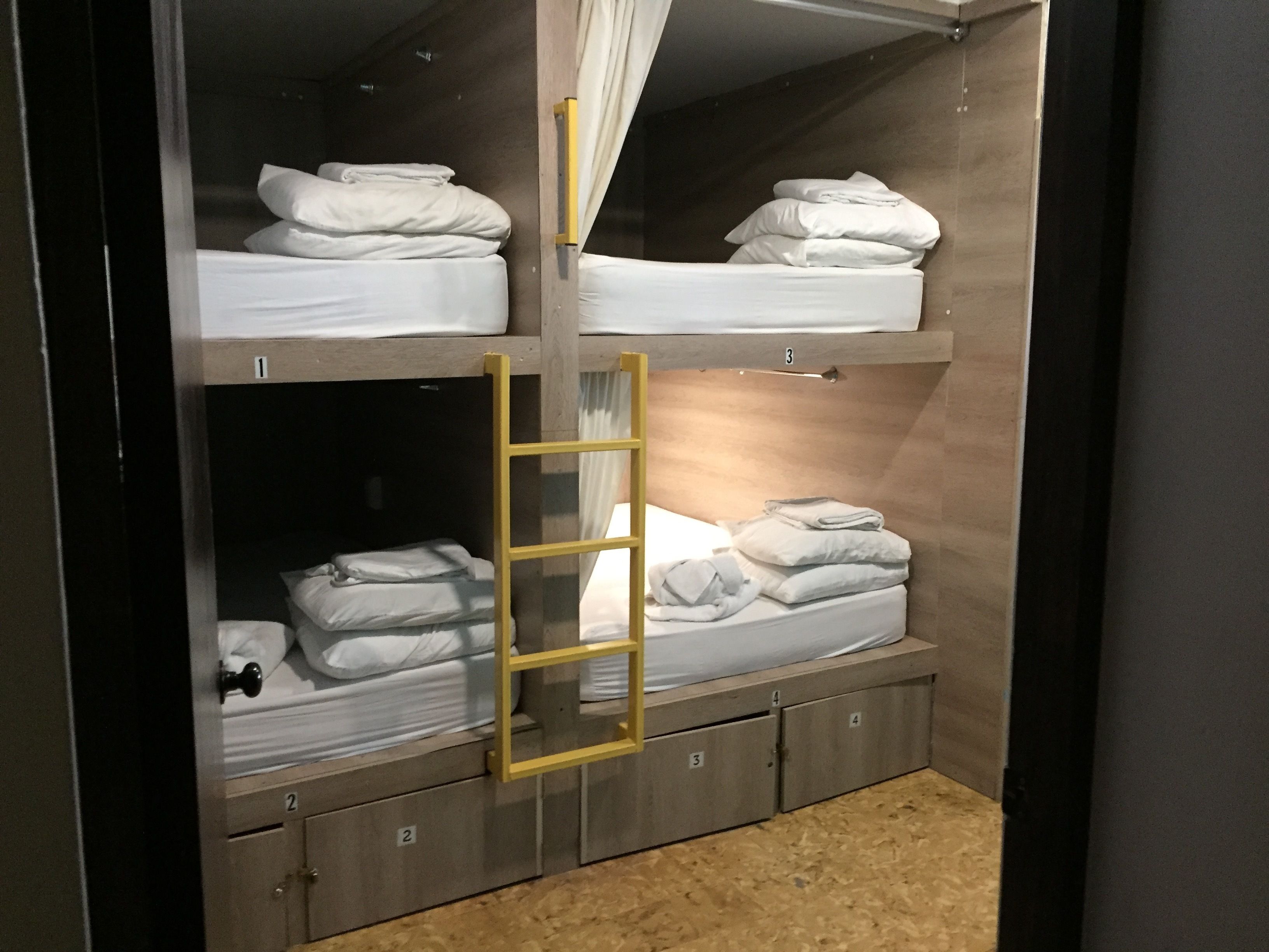 Habitación con literas, compartimentos de almacenamiento numerados y una cortina.