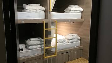 Habitación con literas, compartimentos de almacenamiento numerados y una cortina.