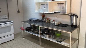A kitchen with a stove, shelves with kitchenware, and a coffee maker. - Hostel the pod 33 (Panama City)