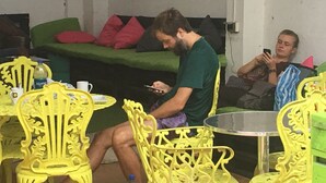 A room with yellow chairs, a green sofa, and a person sitting at a table. - Hostel the pod 33 (Panama City)