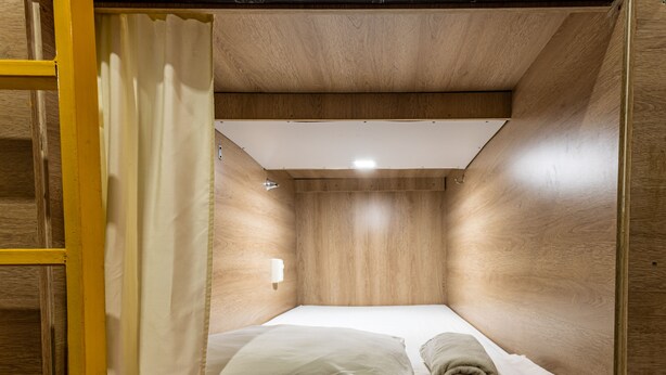 A compact, wooden-paneled room with a single bed, a small window, and a curtain. - Hostel the pod 33 (Panama City)