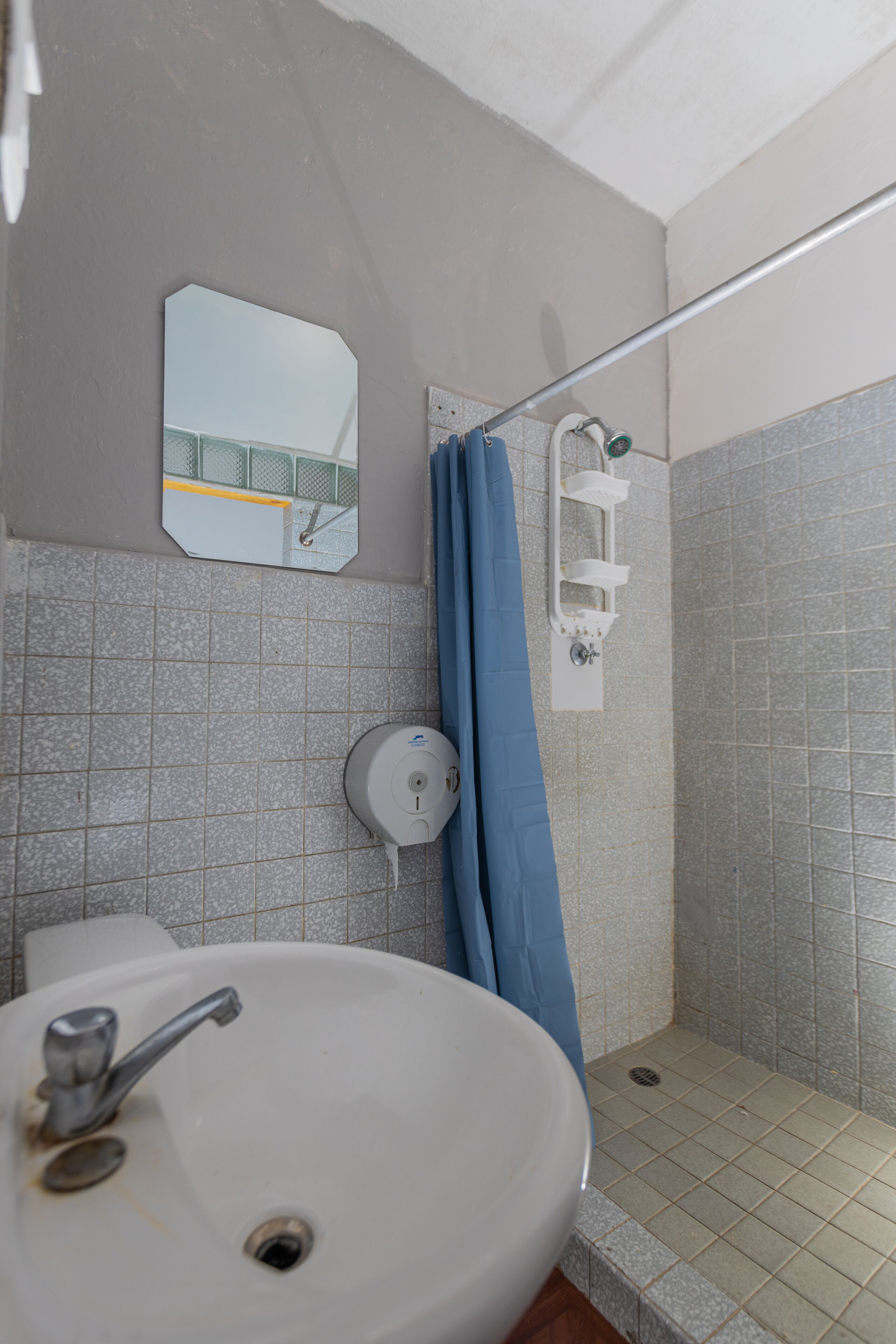 Une salle de bain équipée d’un lavabo, d’un miroir, d’une douche et d’un sèche-mains.