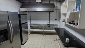 A kitchen with stainless steel appliances, a tiled floor, and a ceiling with a skylight. - Hostel the pod 33 (Panama City)
