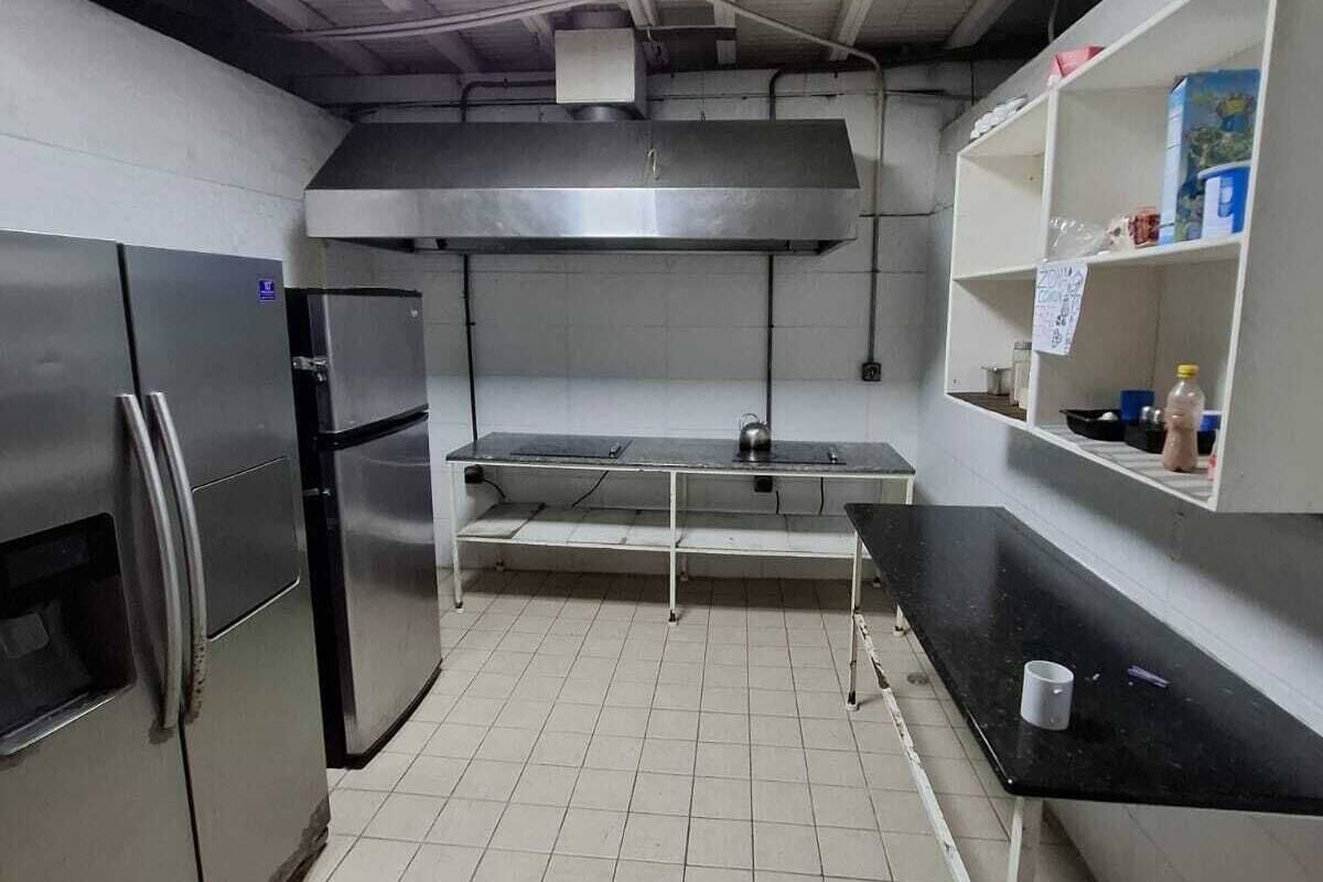 A kitchen with stainless steel appliances, a tiled floor, and a ceiling with a skylight.