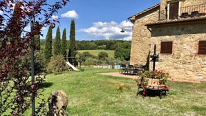 Ein Steinhaus mit Terrasse, Sitzgelegenheiten im Freien und Blick auf die Landschaft.