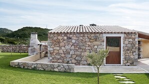 A stone building with a tiled roof, a wooden door, and a small tree in the foreground. - "Mirto" house in the Stazzu Gallurese style in the countryside only 3.5 km from the sea (Rena Majore Aglientu)