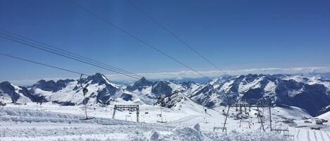 A snow-covered mountain landscape with ski lifts and a clear sky.