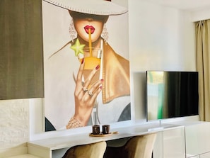 A modern living room with a large abstract painting, a flat-screen TV, and a white console table.
