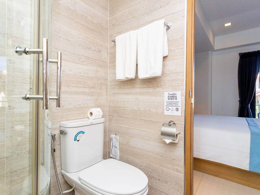 Une salle de bain avec des toilettes, une douche et un lit.