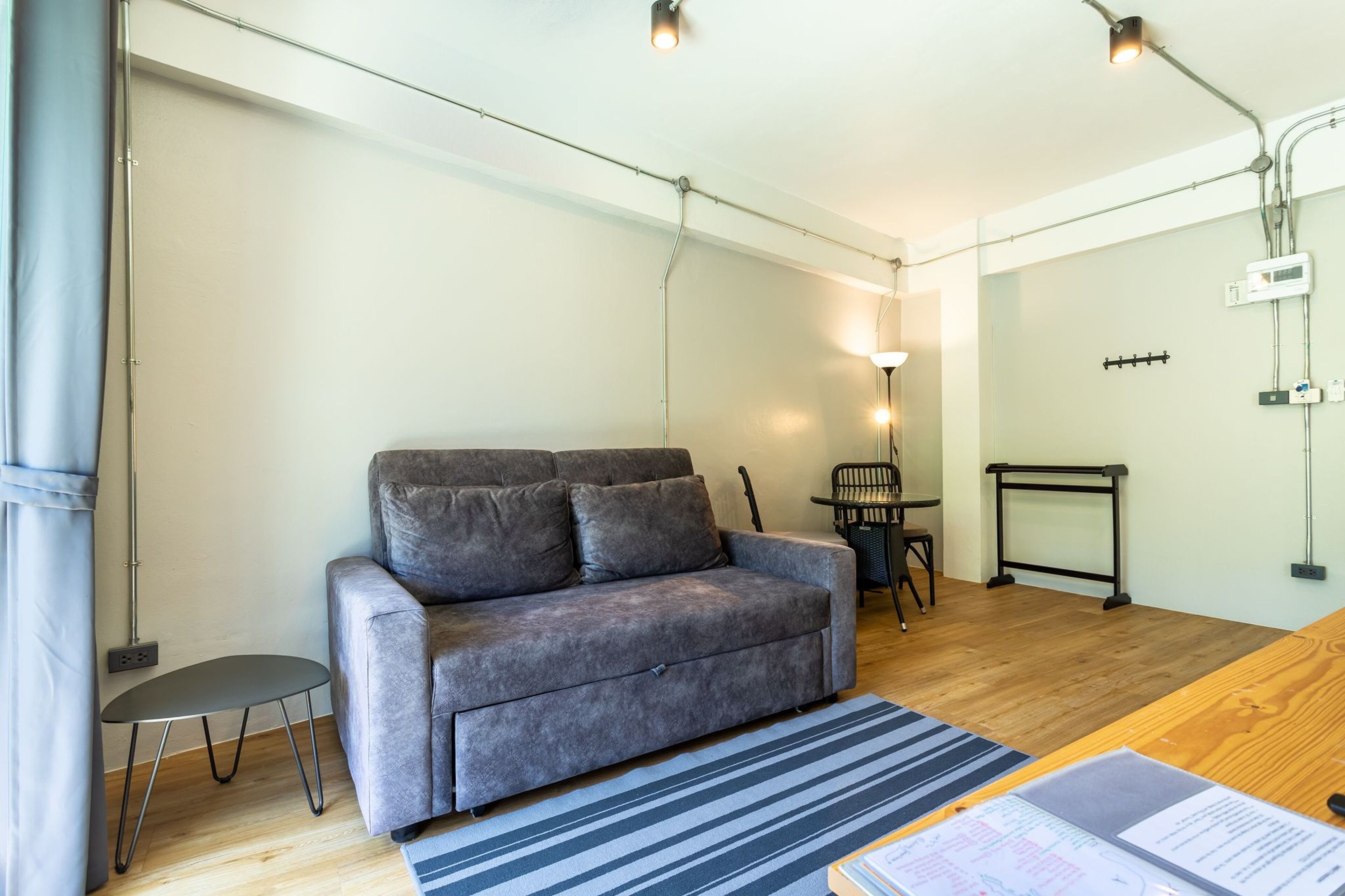 Una sala de estar moderna con un sofá gris, una mesita auxiliar pequeña, un tapete a rayas y una mesa de centro de madera.