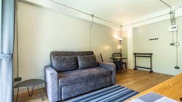 Una sala de estar moderna con un sofá gris, una mesita auxiliar pequeña, un tapete a rayas y una mesa de centro de madera.