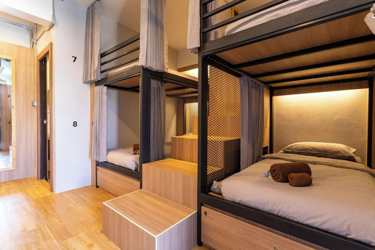 A room with bunk beds, a wooden bench, and a small table.