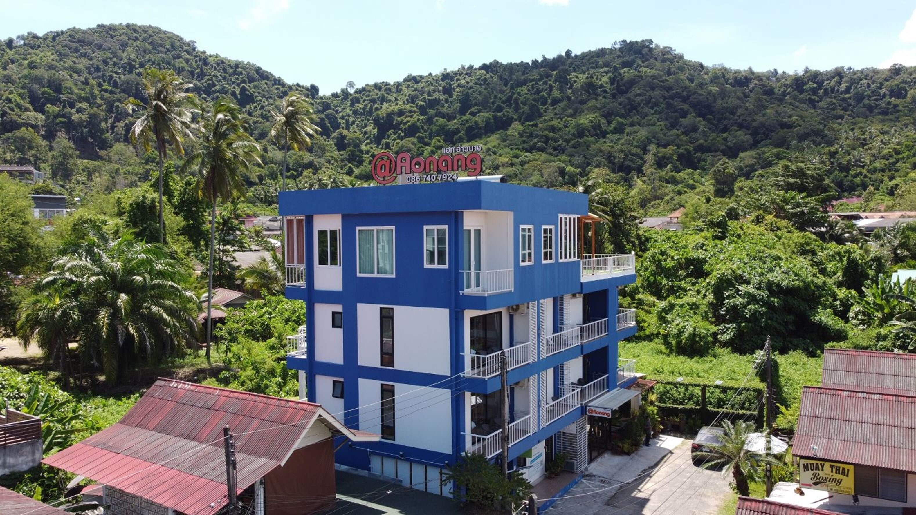 A two-story building with a blue and white facade, balconies, and a sign that reads "Aonang".