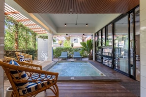 A pool area with wicker chairs, a glass-enclosed patio, and a view of the surrounding neighborhood. - Aonang Guesthouse (Krabi)