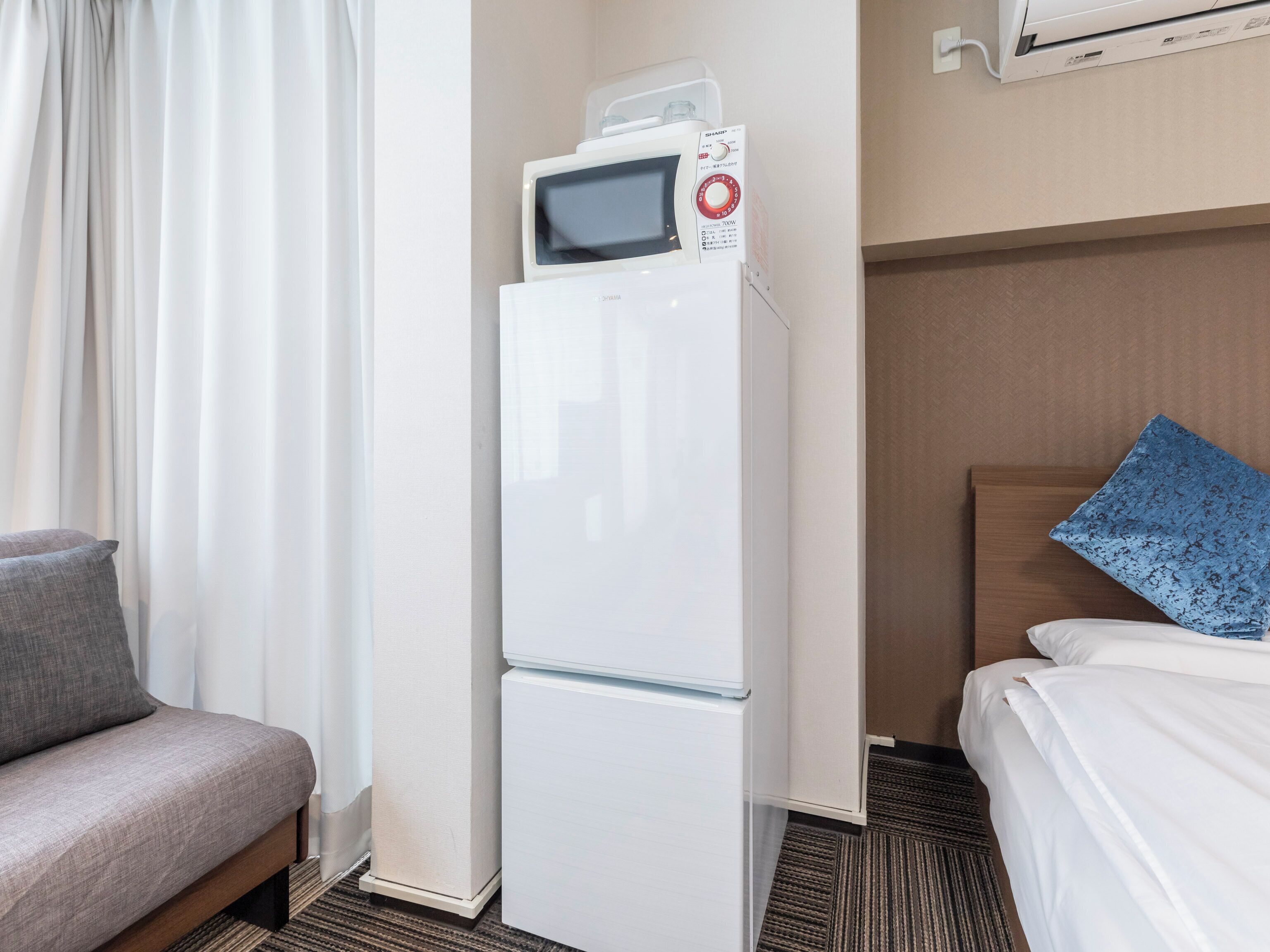 Une chambre d’hôtel équipée d’un lit, d’un canapé, d’un réfrigérateur et d’un appareil de climatisation.
