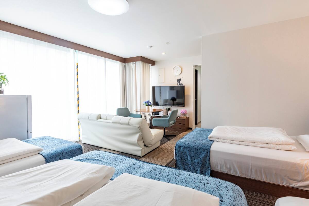 A hotel room with two beds, a desk, a television, and a large window.