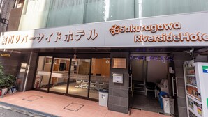 A hotel entrance with a sign for "Sakuragawa Riverside Hotel" and a reception area visible inside. - Tabist Sakuragawa River Side Hotel (Osaka)