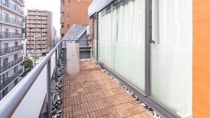 A balcony with a wooden floor, a metal railing, and a glass door. - Tabist Sakuragawa River Side Hotel (Osaka)