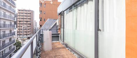 A balcony with a wooden floor, a metal railing, and a glass door.