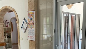 A hallway with a tiled floor, a door with a metal gate, and a calendar on the wall. - Charming holiday home Casa Belitta in Javea / Costa Nova (Xàbia)