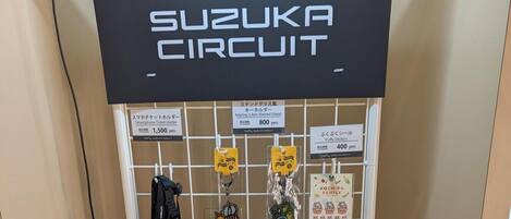 A wall with a 'Suzuka Circuit' sign and various items for sale including keychains and stickers.