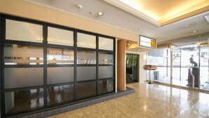 Een schone, moderne lobby met een koffiebar genaamd 'Coffee' en een restaurant genaamd 'Restaurant'.