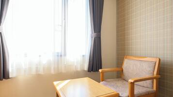 Una habitación con una silla de madera y una pequeña mesa, una ventana con cortinas, y una pared con diseño.