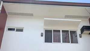 A two-story building with a balcony, a table with chairs, and a bicycle. - Mactan Transient Townhouse (Lapu-Lapu)