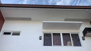 A two-story building with a white facade, a brown lower section, and a window with a view of the sky. - Mactan Transient Townhouse (Lapu-Lapu)