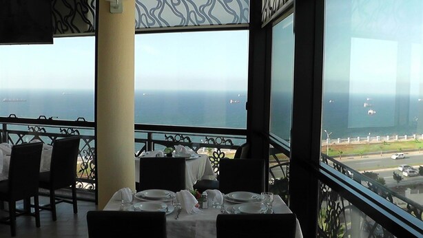 A restaurant with a table set for two, overlooking a coastal view. - Fantazia Hotel (Oran)