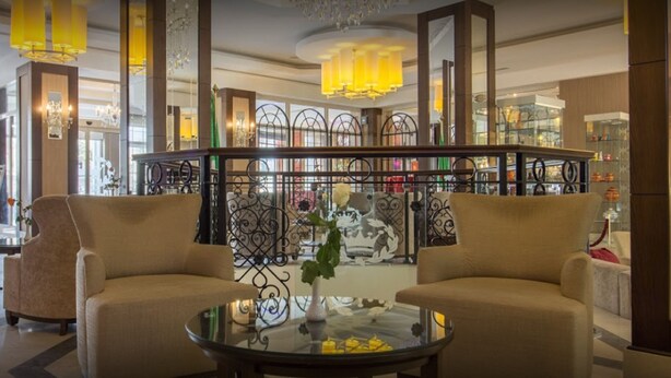 Un hall d’entrée avec deux canapés, une table basse en verre et une rambarde décorative.