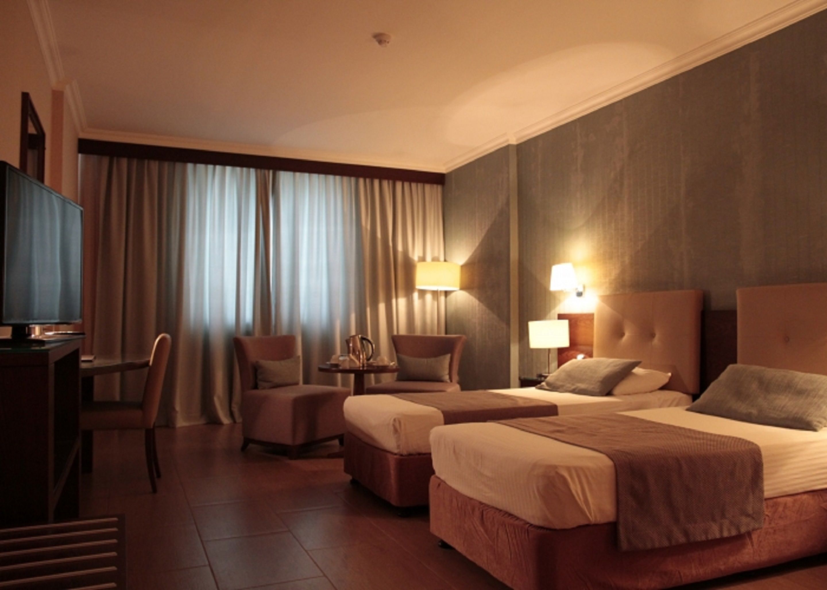 A hotel room with two beds, a TV, a desk, and a chair.