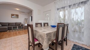 Un coin repas avec une table dressée pour six personnes, entourée de chaises en bois. Un bol bleu se trouve sur la table.