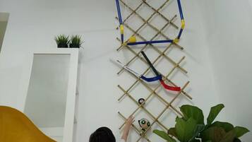 Een kind klimt op een ladderconstructie aan de muur, met een basketbalring bovenop.