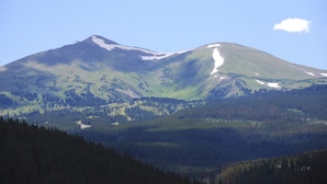 A mountain with a snow-capped peak and a forested valley below. - Five Star Grand Lodge @ Peak 7:  Week of July 4th! (Breckenridge)