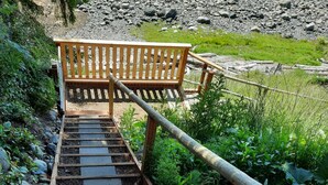 Eine hölzerne Bank oben an einer Steintreppe, die zu einem felsigen Gelände führt.