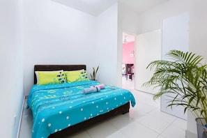 A bedroom with a bed, pillows, a plant, and a view of a pink room.