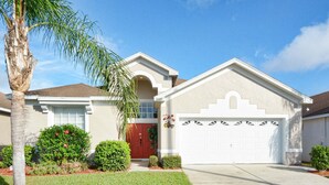 A residential house with a garage, a red door, and a well-maintained lawn. - Family friendly, 10 mins to Disney, WIFI, Resort style amenities, Backyard pool (Kissimmee)