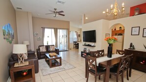 A spacious living room with a sofa, coffee table, and dining area. - Family friendly, 10 mins to Disney, WIFI, Resort style amenities, Backyard pool (Kissimmee)