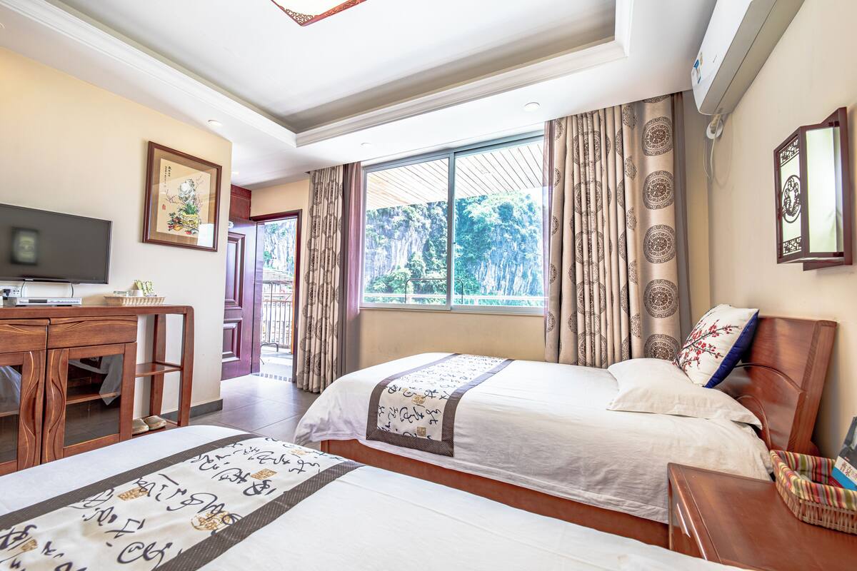 A hotel room with a bed, a desk, a television, and a window with curtains.