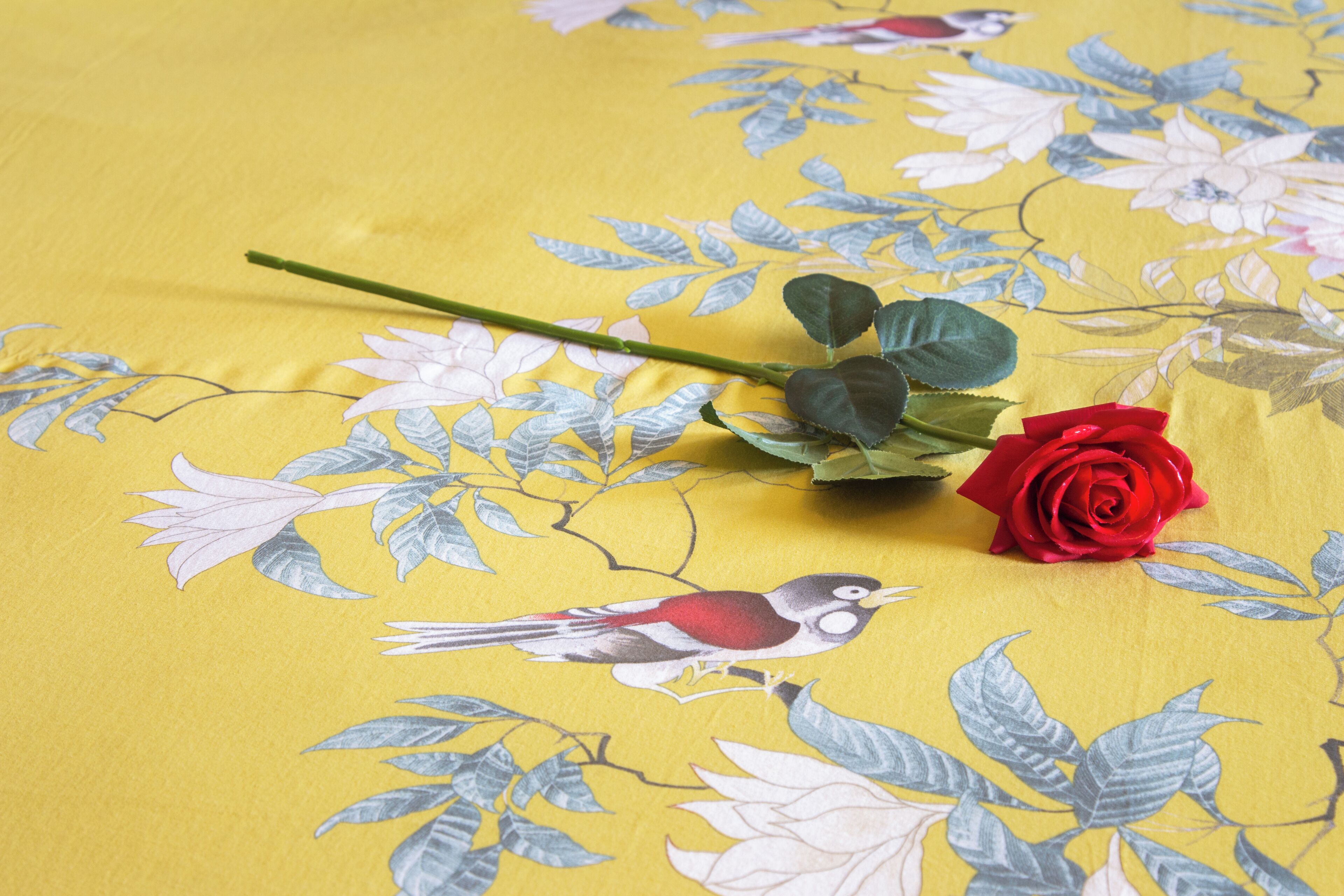 A yellow fabric with floral and bird patterns.
