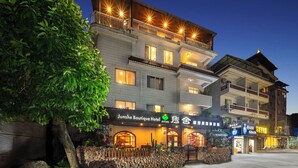 A multi-story building with a sign for 'Junshe Boutique Hotel' and balconies with railings.