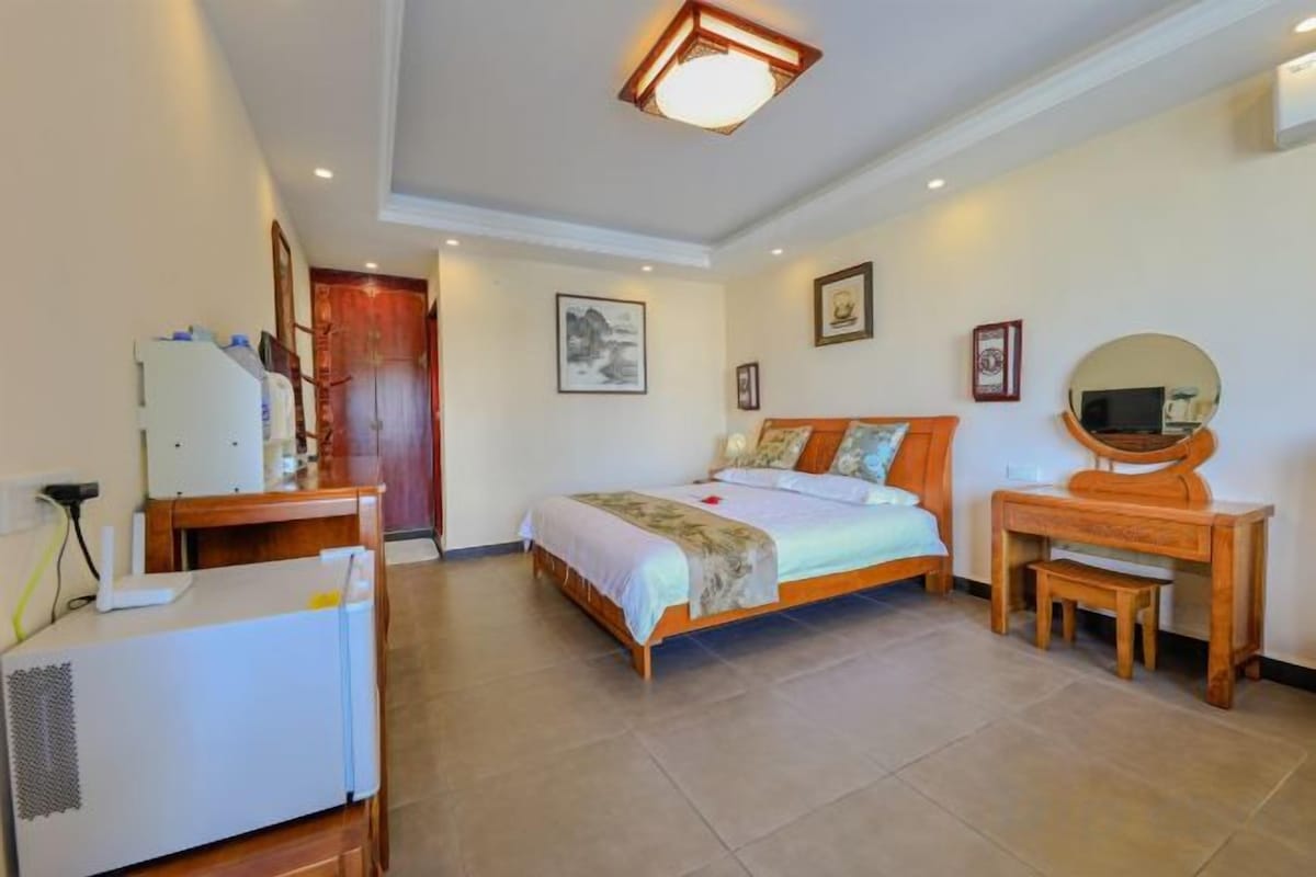 A bedroom with a bed, bedside table, desk, and a mirror.
