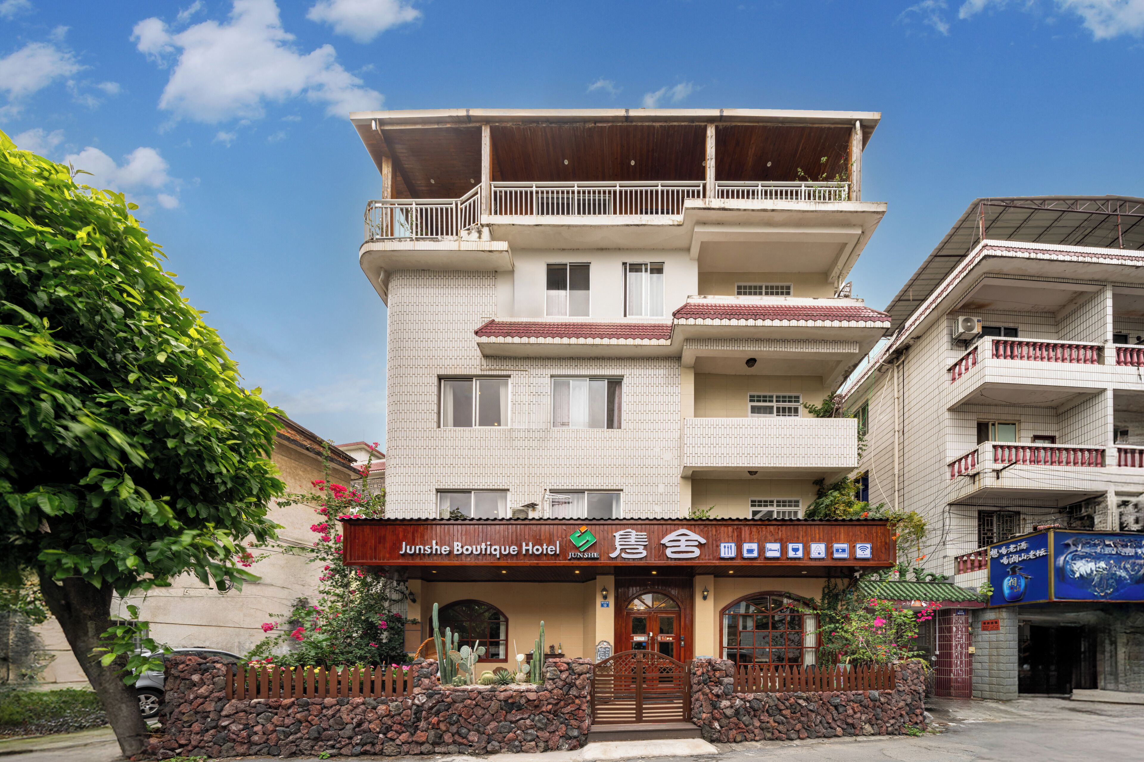 A multi-story hotel with a sign reading 'Junshe Boutique Hotel.'