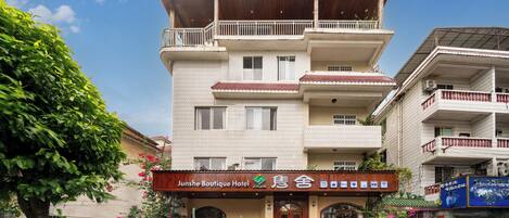 A multi-story hotel with a sign reading 'Junshe Boutique Hotel.'
