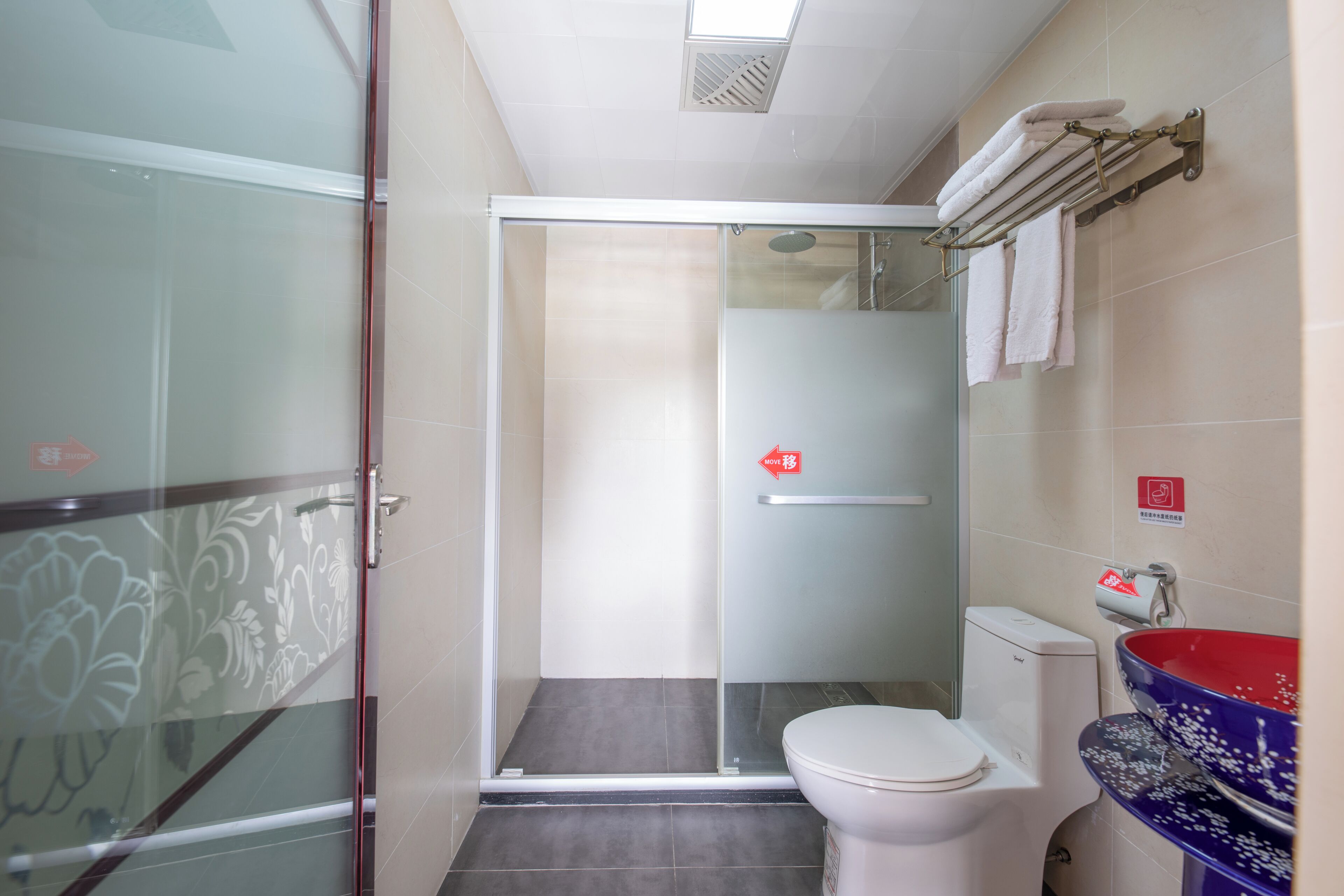 Une salle de bain dotée d’une douche à parois de verre, de toilettes et d’un lavabo avec un receveur décoratif.