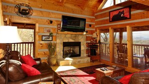 A cozy cabin interior with a stone fireplace, leather furniture, and a mounted television. - dream catcher. Beautiful Mountain Veiws and Real Log Cabin Charm! (Sevierville)