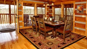 A wooden dining room with a large table, chairs, and a patterned rug. - dream catcher. Beautiful Mountain Veiws and Real Log Cabin Charm! (Sevierville)