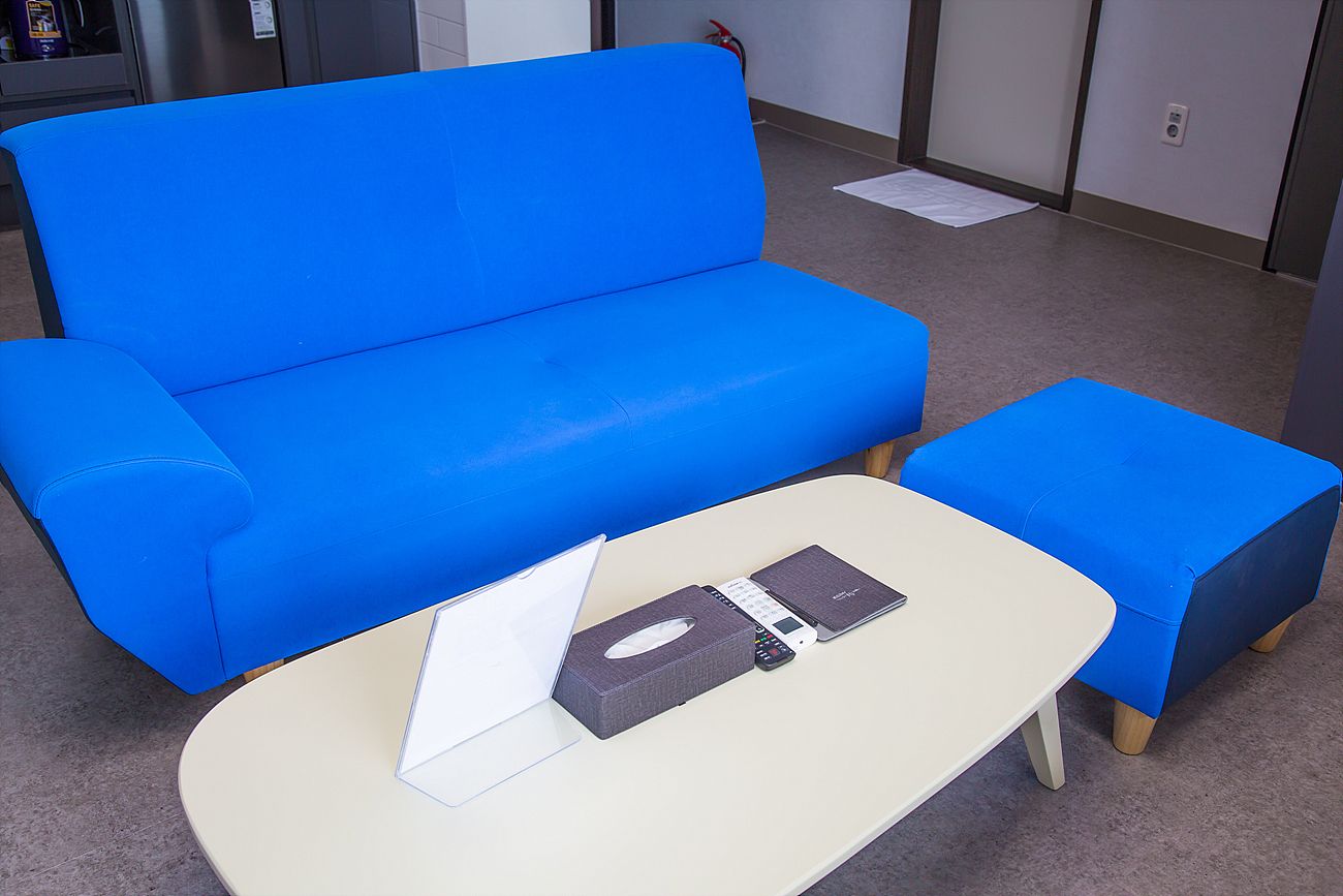 A blue sofa and a matching ottoman in a room with a white table.