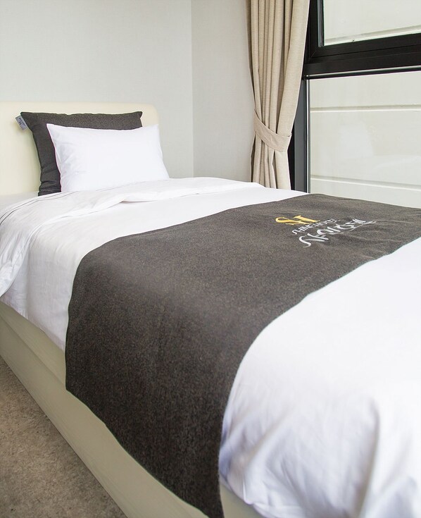 A neatly made bed with a white headboard, a dark grey blanket, and a white pillow. - Shine Hotel (Suncheon)
